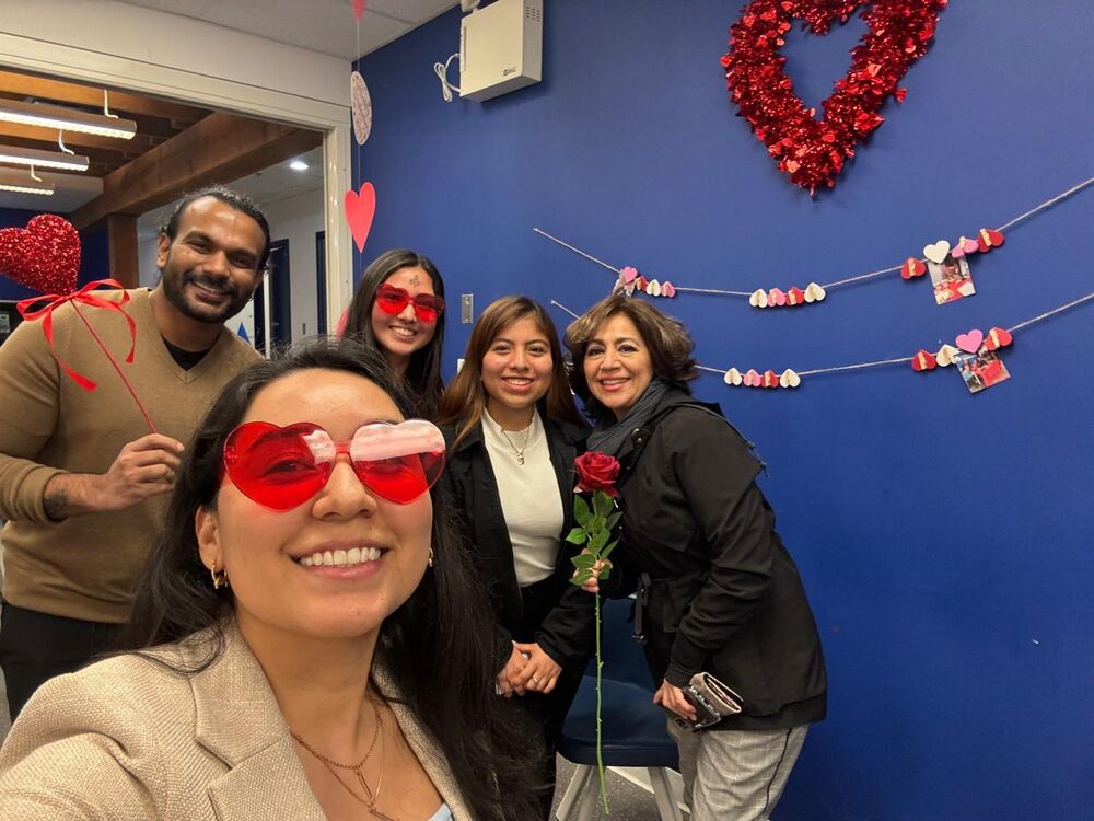 Ninfa Segovia sonriendo con amigos, con lentes en forma de corazón y una rosa